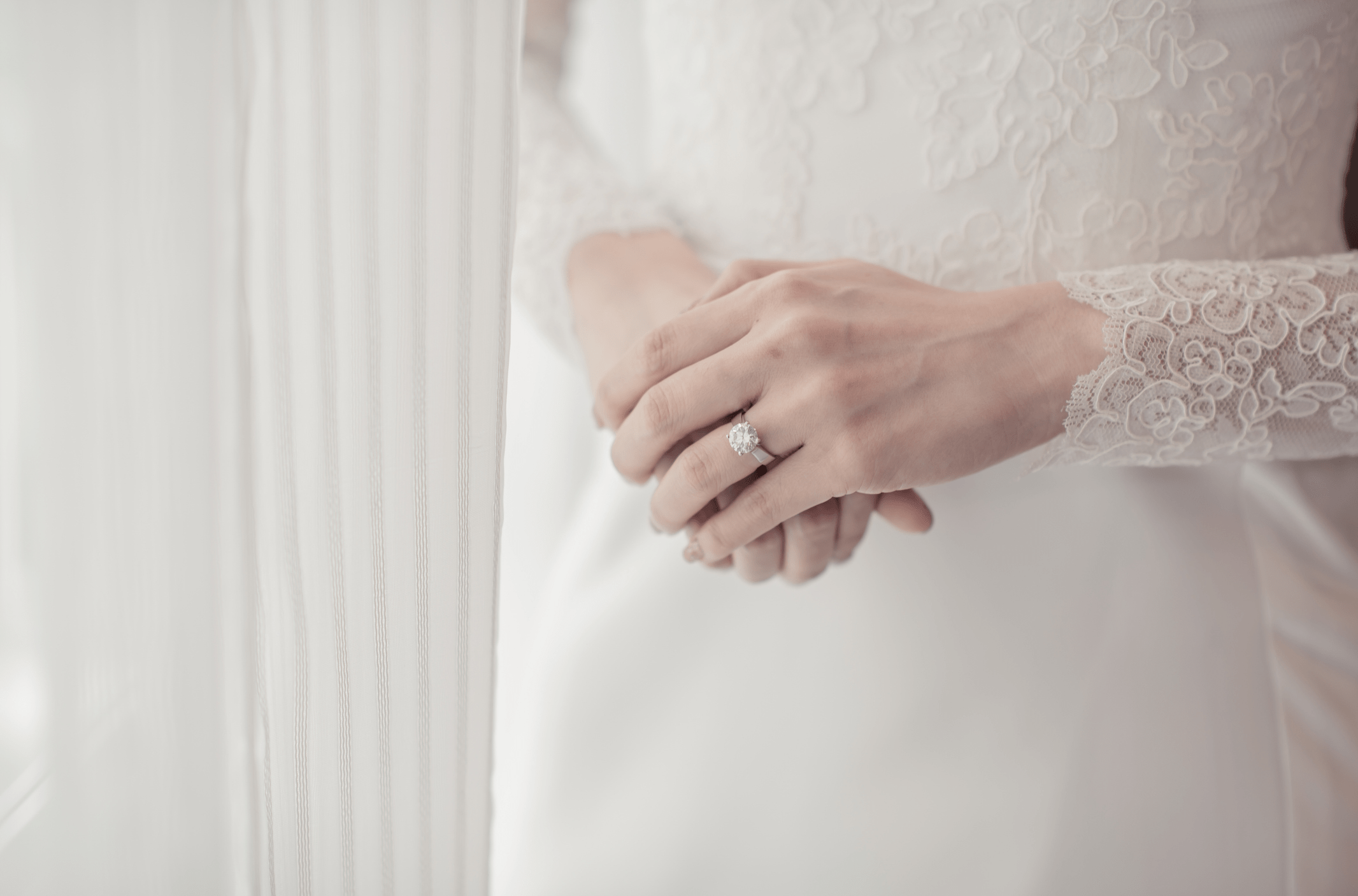 A beautiful bride wearing a "Kronjuvel" ring adorned with a single sparkling diamond. The elegant ring graces her finger, complementing her bridal attire and adding a touch of timeless sophistication to her look.